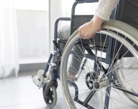 Person im Rollstuhl vor Balkontür