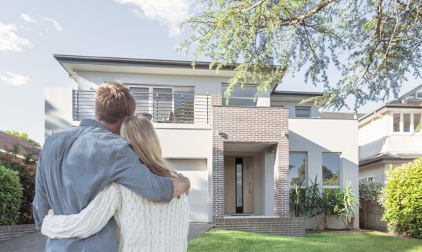 Junges Paar schaut auf Ihr neues Haus mit UNILUX Holzhaustür