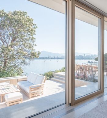 Blick auf Terrasse am See durch geöffnete UNILUX Holz-Alu Hebe-Schiebeanlage