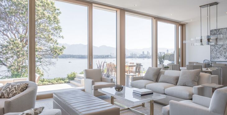 Blick aus hellem Wohnraum auf Terrasse und See durch UNILUX Holz-Alu Hebe-Schiebeanlage