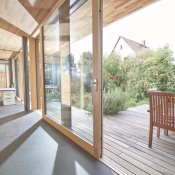 Büroraum mit geöffneter UNILUX Holz-Alu Hebe-Schiebe Anlage und Blick auf Terrasse